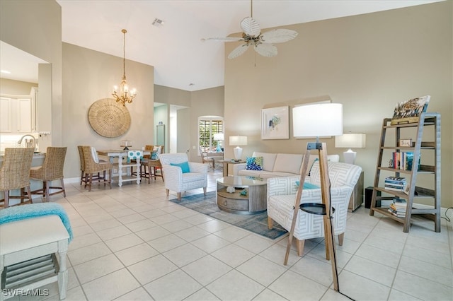 living room featuring light tile patterned floors, ceiling fan with notable chandelier, and a high ceiling