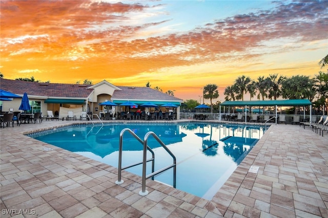 pool at dusk featuring a patio area