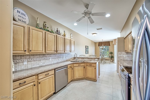 kitchen featuring light stone countertops, appliances with stainless steel finishes, tasteful backsplash, sink, and pendant lighting