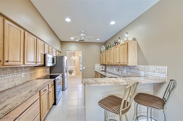 kitchen featuring a kitchen breakfast bar, kitchen peninsula, light brown cabinetry, and appliances with stainless steel finishes