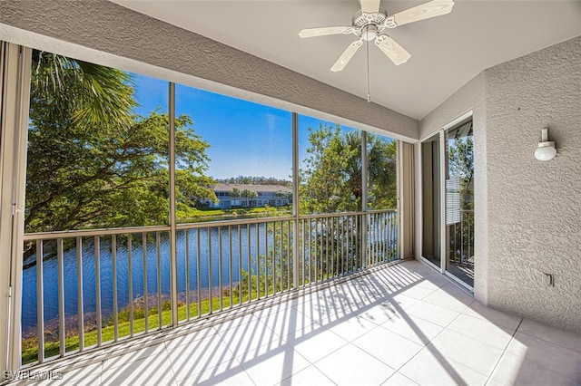 unfurnished sunroom featuring ceiling fan and a water view