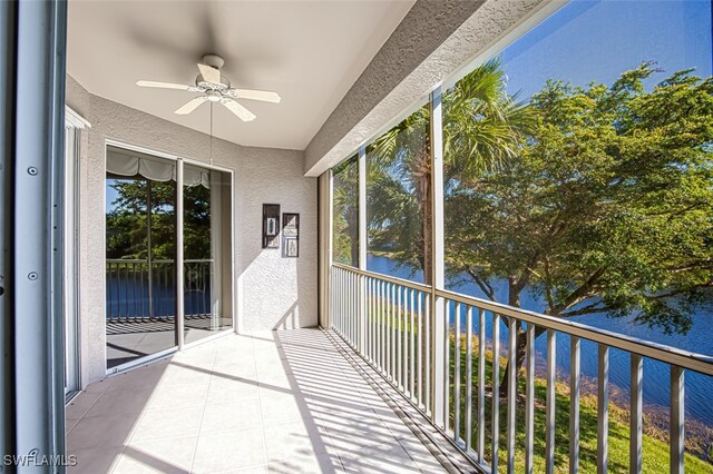 unfurnished sunroom featuring ceiling fan and a water view