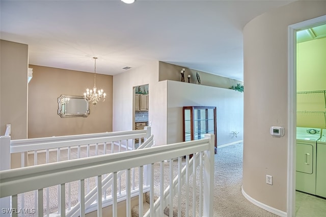 hall featuring washing machine and dryer, light carpet, and an inviting chandelier