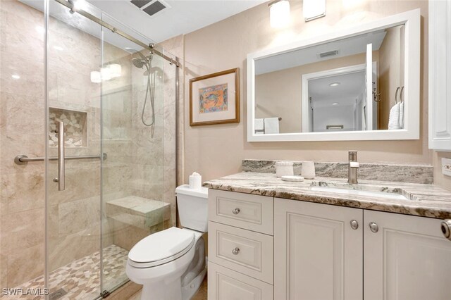 bathroom with vanity, toilet, and a shower with shower door