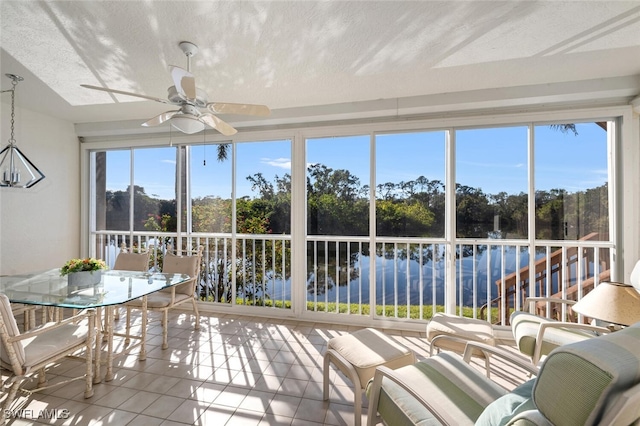 sunroom / solarium featuring a water view and ceiling fan