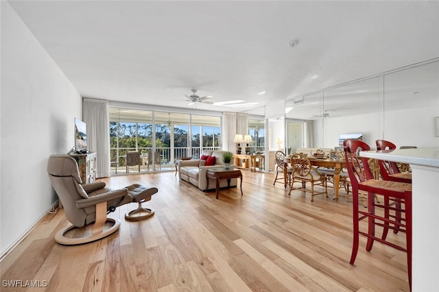 living room featuring ceiling fan, floor to ceiling windows, and light hardwood / wood-style flooring