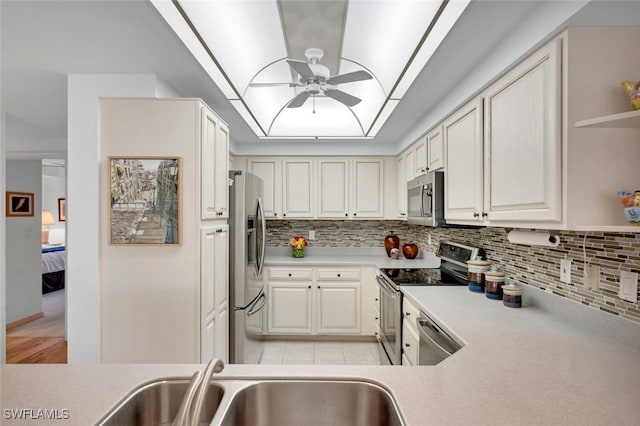 kitchen featuring decorative backsplash, appliances with stainless steel finishes, ceiling fan, sink, and white cabinetry