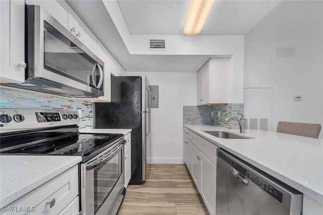 kitchen with white cabinetry, sink, light stone countertops, backsplash, and appliances with stainless steel finishes