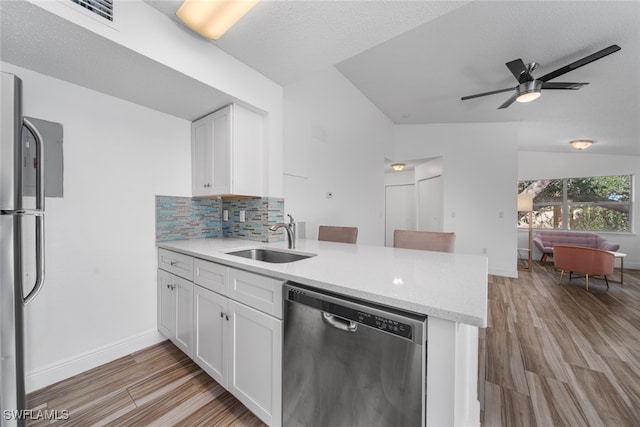 kitchen featuring lofted ceiling, sink, light hardwood / wood-style flooring, appliances with stainless steel finishes, and white cabinetry