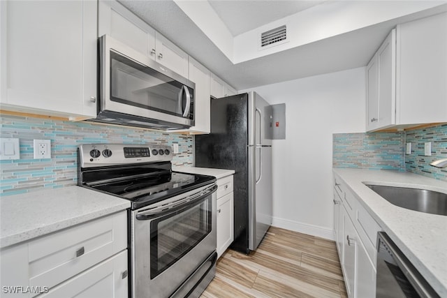 kitchen featuring light stone countertops, appliances with stainless steel finishes, tasteful backsplash, sink, and white cabinetry