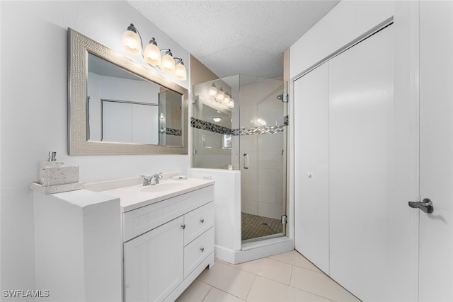 bathroom with tile patterned floors, vanity, an enclosed shower, and a textured ceiling