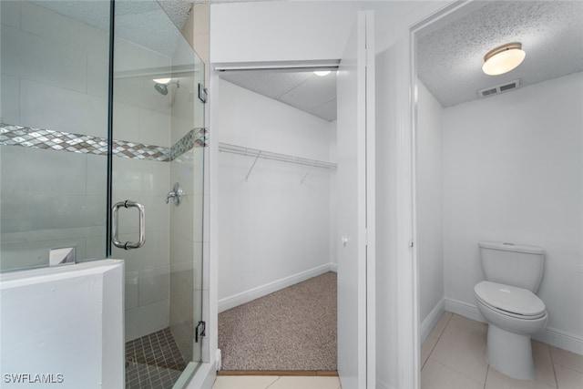 bathroom with toilet, a textured ceiling, tile patterned floors, and walk in shower