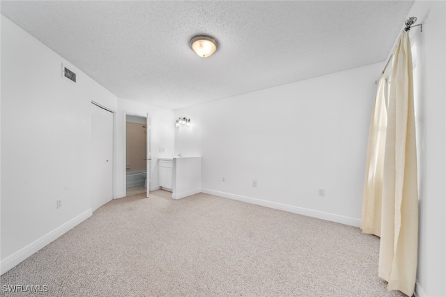 unfurnished bedroom featuring a textured ceiling and light colored carpet