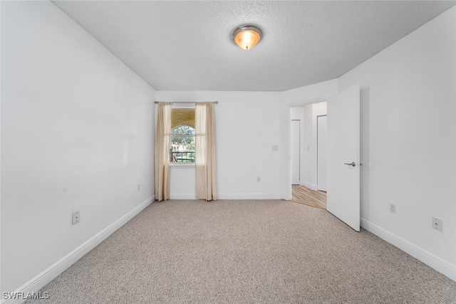 unfurnished room featuring light carpet and a textured ceiling