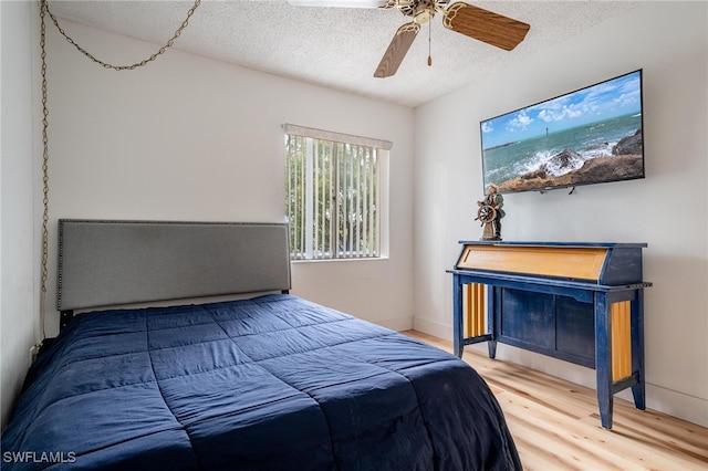 bedroom featuring ceiling fan, hardwood / wood-style floors, and a textured ceiling