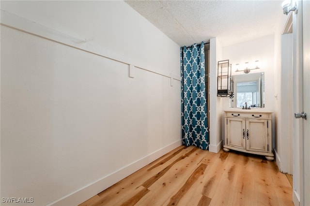 bathroom featuring hardwood / wood-style flooring, vanity, walk in shower, and a textured ceiling