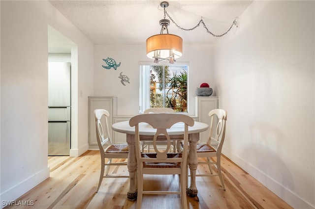 dining space with a textured ceiling and light wood-type flooring