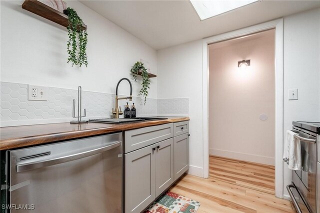 kitchen featuring gray cabinets, appliances with stainless steel finishes, sink, backsplash, and light hardwood / wood-style flooring