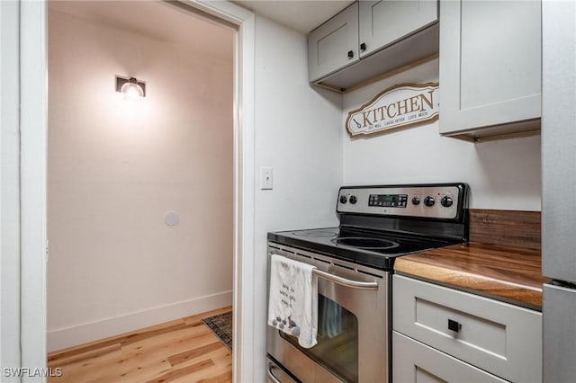 kitchen with stainless steel electric range oven and light hardwood / wood-style flooring