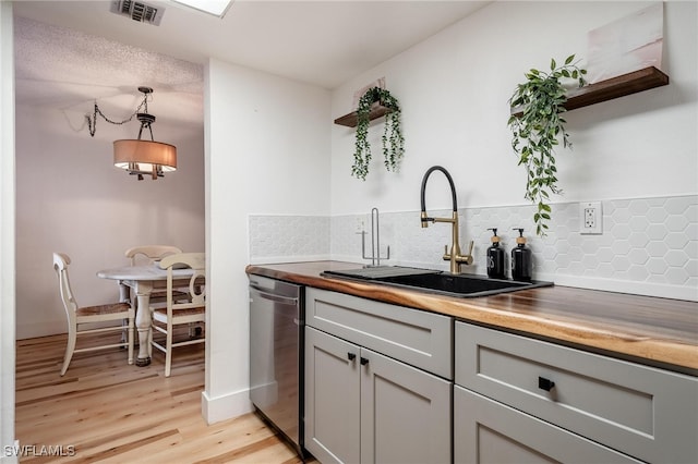 kitchen featuring sink, dishwasher, gray cabinetry, backsplash, and hanging light fixtures