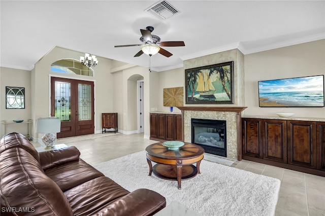 living room featuring french doors, ceiling fan with notable chandelier, ornamental molding, and light tile patterned flooring