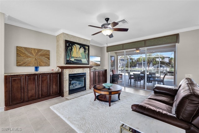 living room with a fireplace, ceiling fan, light tile patterned floors, and crown molding