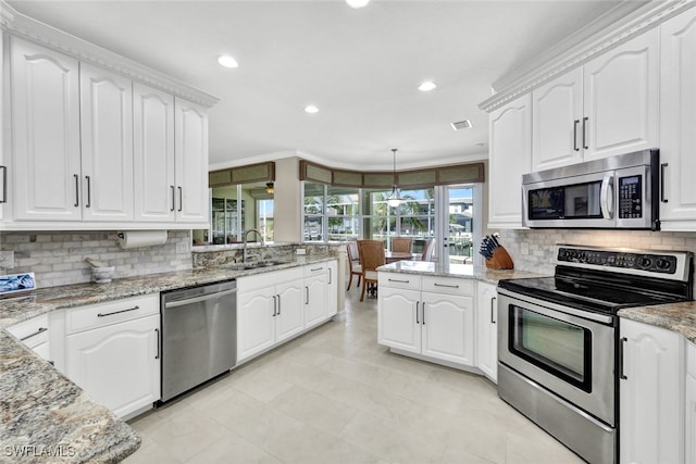 kitchen featuring light stone countertops, white cabinets, ornamental molding, and appliances with stainless steel finishes