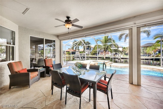 sunroom / solarium featuring ceiling fan and a water view