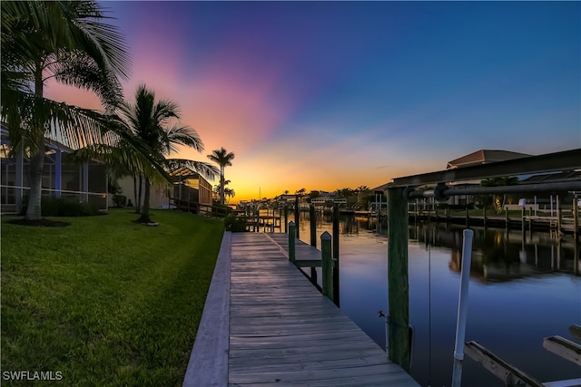 view of dock with a water view and a yard