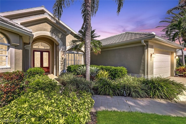 exterior entry at dusk with a garage and french doors