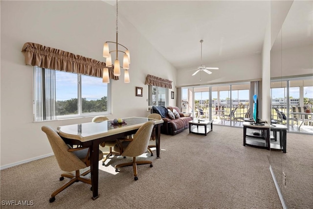 carpeted dining area featuring high vaulted ceiling, a healthy amount of sunlight, baseboards, and ceiling fan with notable chandelier