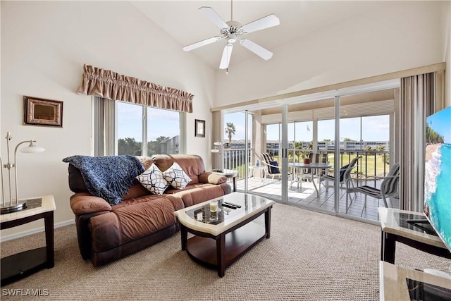 living area with ceiling fan, high vaulted ceiling, carpet flooring, and a healthy amount of sunlight