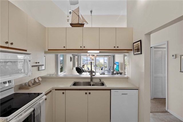 kitchen featuring white appliances, sink, cream cabinetry, light tile patterned flooring, and kitchen peninsula