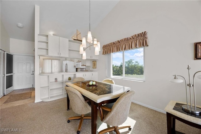 dining space with baseboards, high vaulted ceiling, a notable chandelier, and light colored carpet