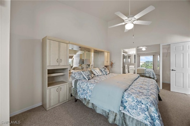 bedroom featuring light carpet, baseboards, a ceiling fan, ensuite bath, and high vaulted ceiling