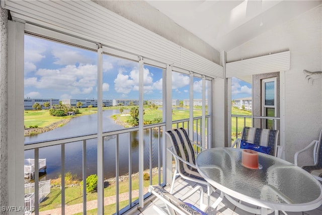 sunroom / solarium with a water view and vaulted ceiling