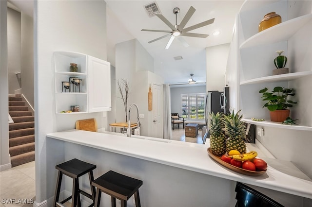 kitchen featuring white cabinets, a kitchen breakfast bar, sink, light tile patterned floors, and kitchen peninsula