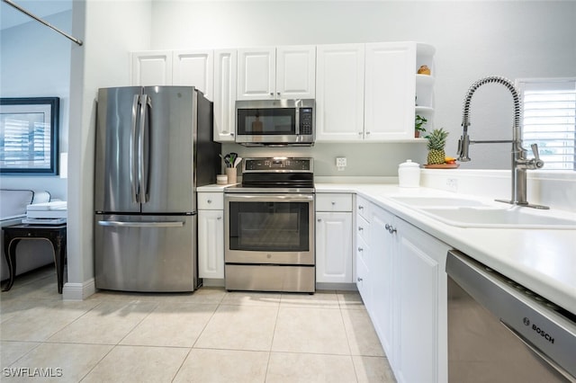 kitchen with light tile patterned flooring, stainless steel appliances, white cabinetry, and sink