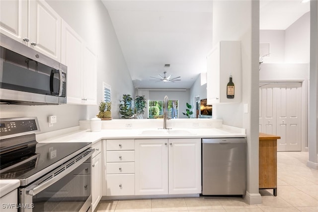 kitchen with sink, light tile patterned floors, lofted ceiling, white cabinets, and appliances with stainless steel finishes