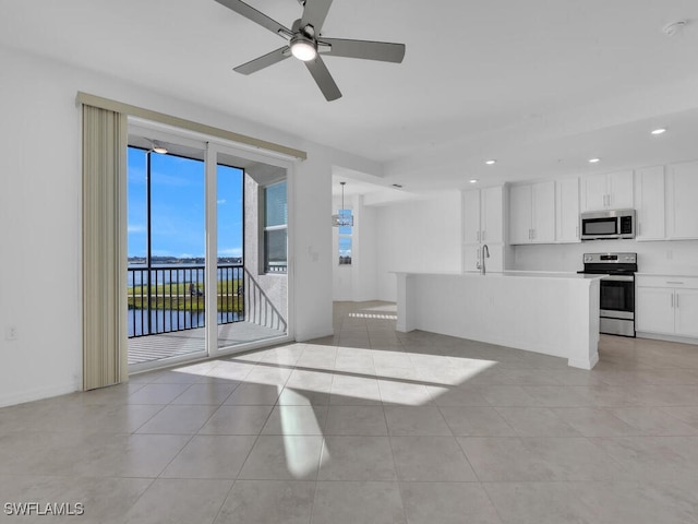 unfurnished living room featuring a water view, ceiling fan, sink, and light tile patterned flooring