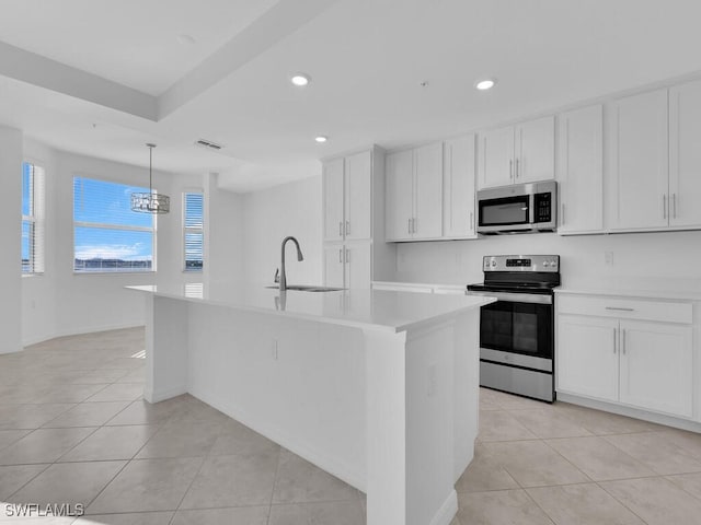 kitchen featuring white cabinets, appliances with stainless steel finishes, a center island with sink, and sink