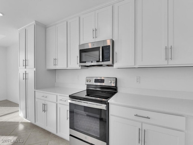 kitchen featuring light tile patterned flooring, white cabinets, and stainless steel appliances