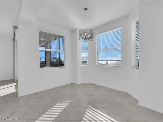 empty room featuring light tile patterned floors, a healthy amount of sunlight, and a notable chandelier