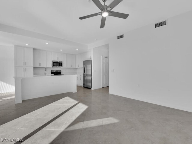 unfurnished living room with ceiling fan, sink, and light tile patterned floors