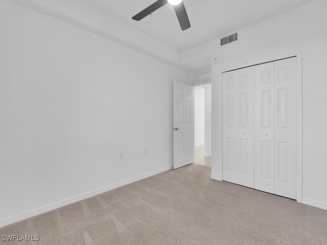 unfurnished bedroom featuring a closet, ceiling fan, and light colored carpet