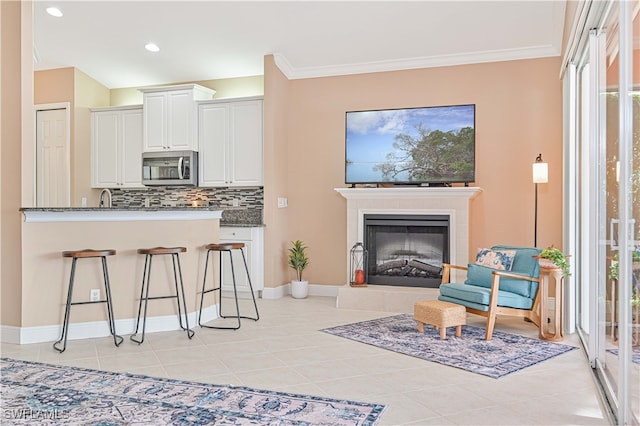 interior space featuring a tiled fireplace, light tile patterned floors, and ornamental molding