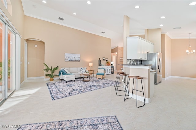 tiled living room featuring crown molding and a notable chandelier