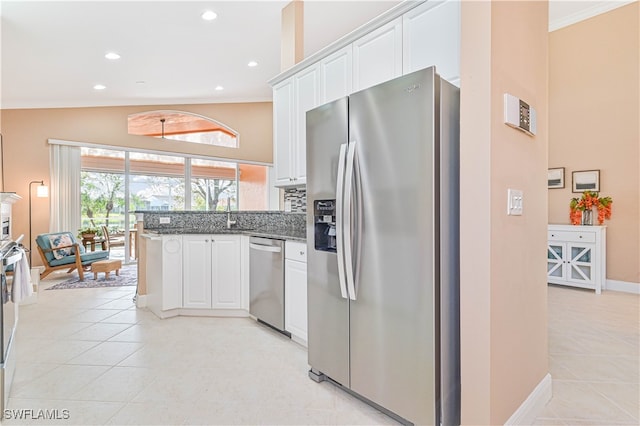 kitchen featuring dark stone counters, white cabinets, ornamental molding, appliances with stainless steel finishes, and light tile patterned flooring