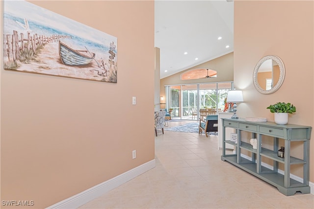 corridor featuring light tile patterned floors and high vaulted ceiling