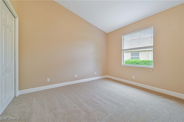 unfurnished room featuring carpet and lofted ceiling